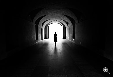Frau geht durch einen dunklen Tunnel ins wei&szlig;e Licht in Prag, Tschechien.