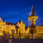 Beleuchteter Samsonbrunnen und historische Gebäude auf dem Marktplatz von Budweis