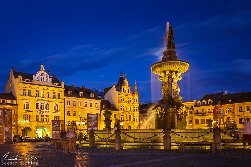 Beleuchteter Samsonbrunnen und historische Gebäude auf dem Marktplatz von Budweis