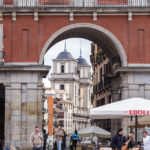 Blick durch ein Zugangstor des Hauptplatzes (Plaza Mayor) von Madrid auf die Stiftskirche San Isidro (Iglesia de San Isidro)