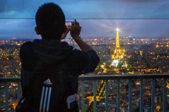 Ein Tourist fotografiert auf der Aussichtsterrasse des Tour Montparnasse in Richtung Eiffelturm