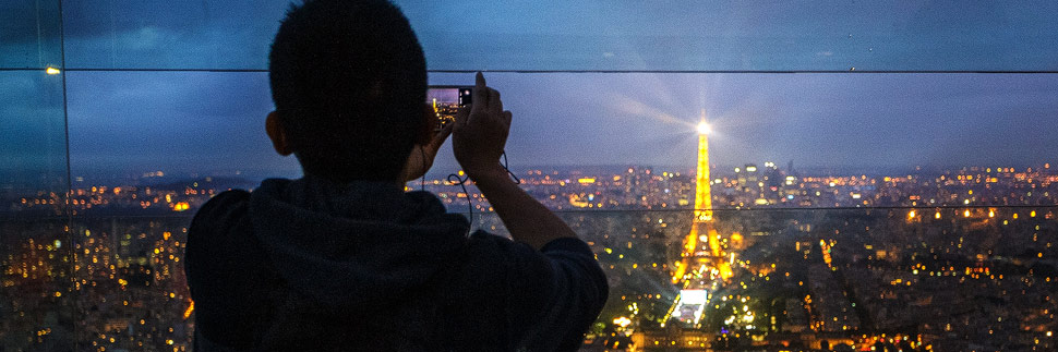 Ein Bub fotografiert den Eiffelturm in der Dämmerung in Paris