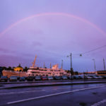 Ein Regenbogen und die untergehende Sonne in der Ferne tauchen Stockholm in ein magisches Licht
