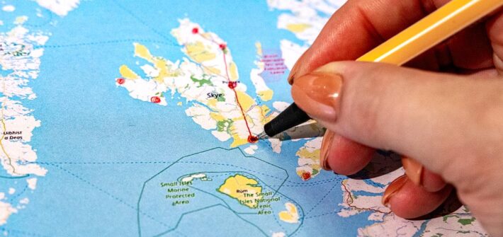 Person zeichnet auf einer Schottland-Karte die Highlights für eine Rundreise ein
