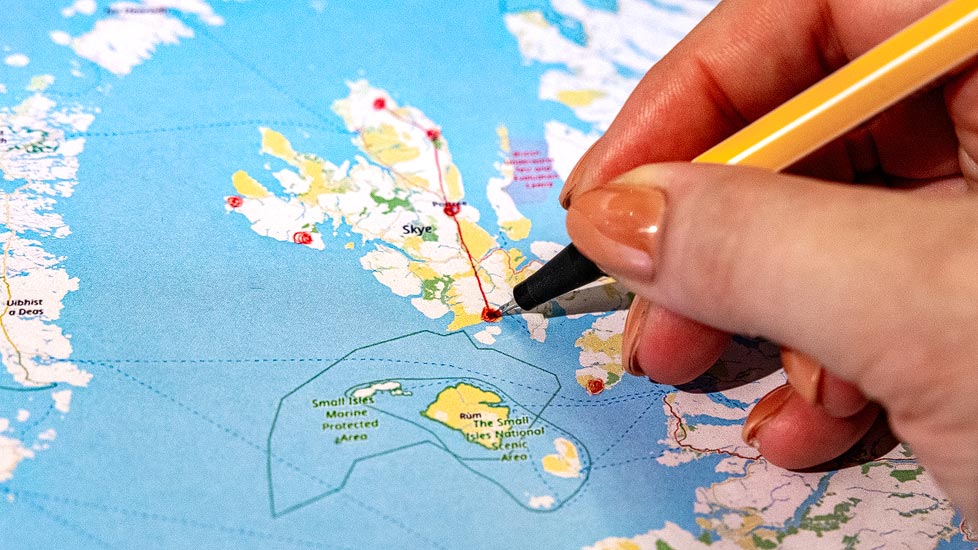 Person zeichnet auf einer Schottland-Karte die Highlights für eine Rundreise ein