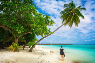 Frau zwischen Palmen am Strand von Meeru (Malediven)