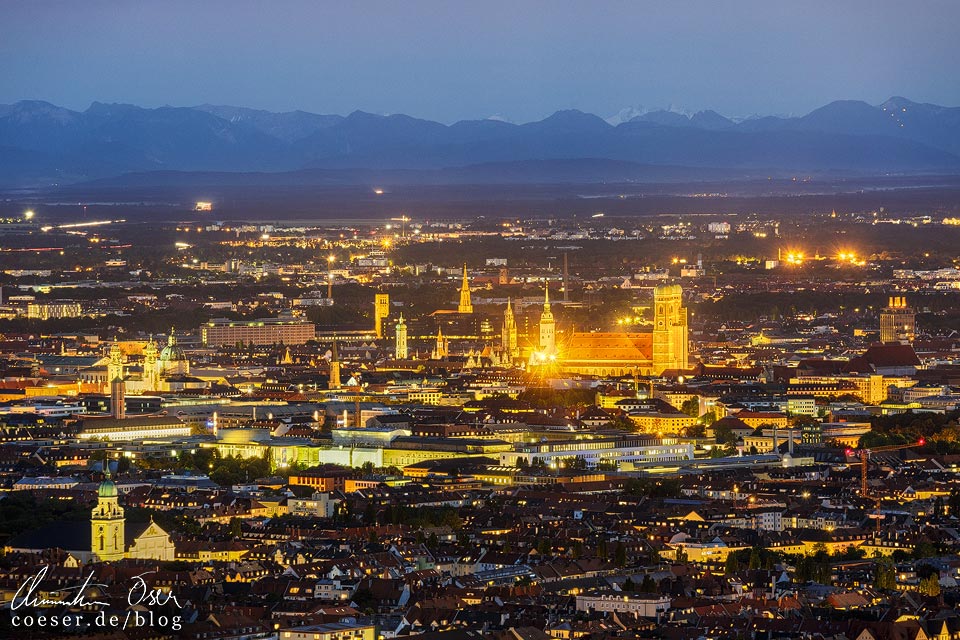 Münchner Innenstadt in der Abenddämmerung mit Gebirgslandschaft im Hintergrund