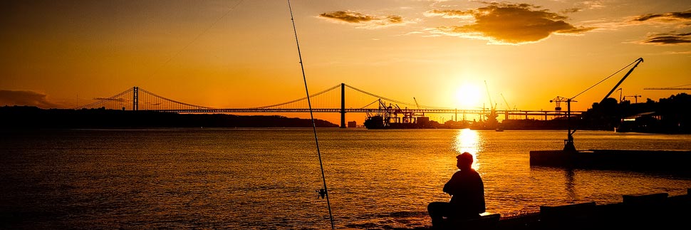 Fischer am Fluss Tajo im Sonnenuntergang in Lissabon