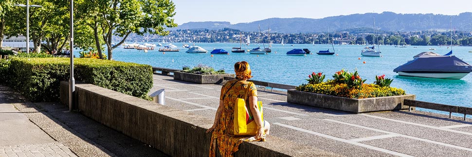 Frau sitzt am Ufer des Zürisee in Zürich
