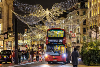 Roter Doppelstockbus zwischen der Weihnachtsbeleuchtung der Regent Street in London