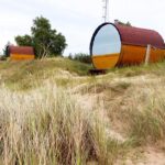 Die Holzfässer in der Unterkunft Kempings Saulesmājas vom Strand aus gesehen in Kap Kolka, Lettland
