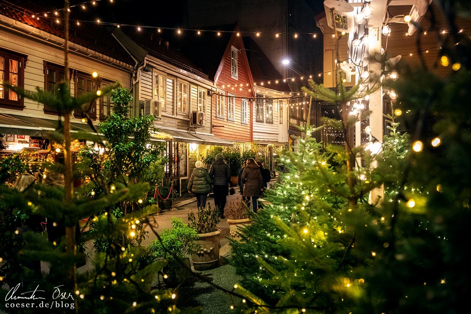 Weihnachtsbeleuchtung in einer kleinen Gasse mit Holzhäusern in der Altstadt von Bergen, Norwegen