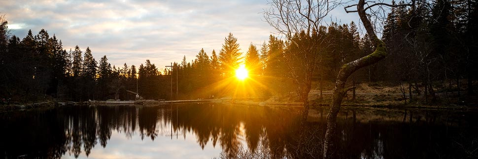Sonnenuntergang über dem See Skomakerdiket auf dem Berg Fløyen in Bergen, Norwegen