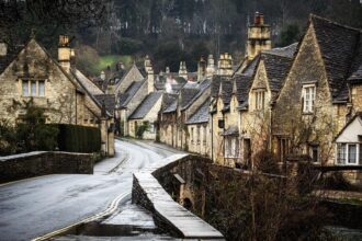 Ein Paar geht im Regen durch Castle Combe in den Cotwolds