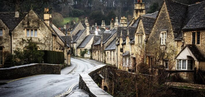 Ein Paar geht im Regen durch Castle Combe in den Cotwolds