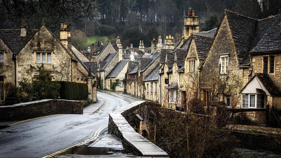Ein Paar geht im Regen durch Castle Combe in den Cotwolds