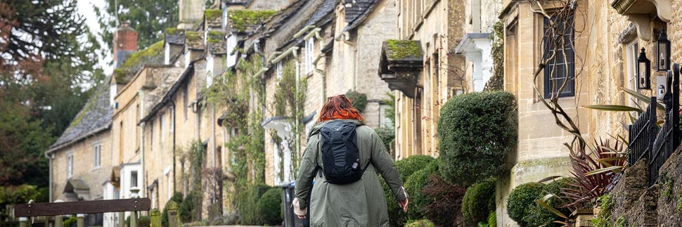 Frau vor historischen Häusern auf der High Street in Burford, Cotswolds