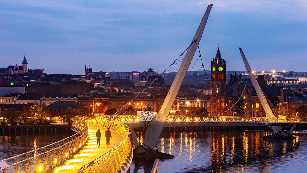 Abendaufnahme der beleuchteten Peace Bridge in Derry-Londonderry, Nordirland