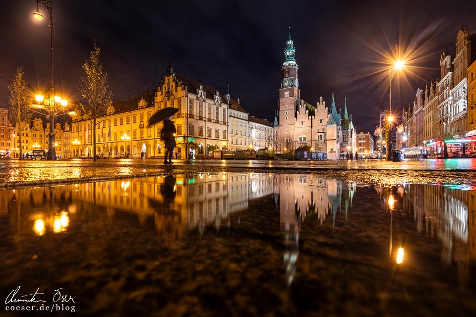 Abendlich beleuchteter Marktplatz Rynek mit Spiegelung nach einem Regenschauer in Wrocław, Polen