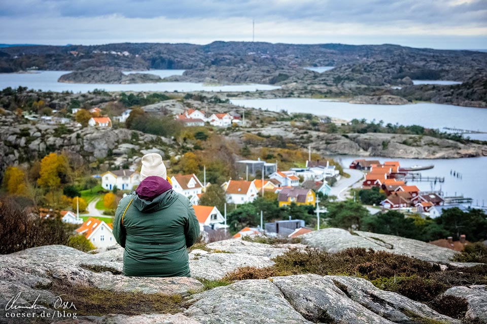 Frau sitzt auf einem Felsen und blickt auf Fjällbacka in der schwedischen Provinz Bohuslän