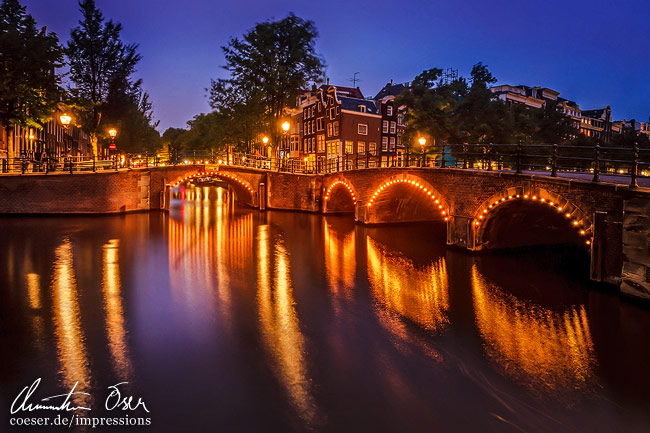 Die beleuchtete Ecke Prinsengracht und Reguliersgracht während der blauen Stunde in Amsterdam, Niederlande.