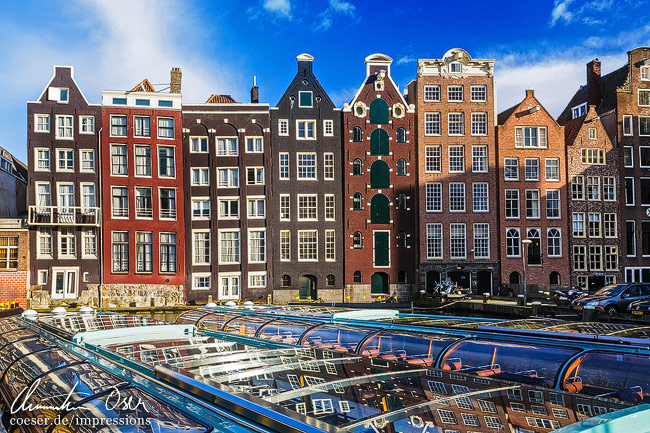 Spiegelung von historischen Gebäuden auf der Straße Damrak in Amsterdam, Niederlande.