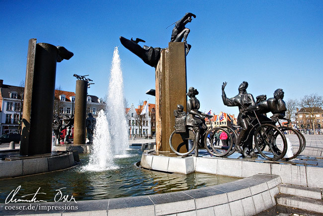 Ein Brunnen mit einer Radfahrerskulptur am 't-Zand-Platz in Brügge, Belgien.