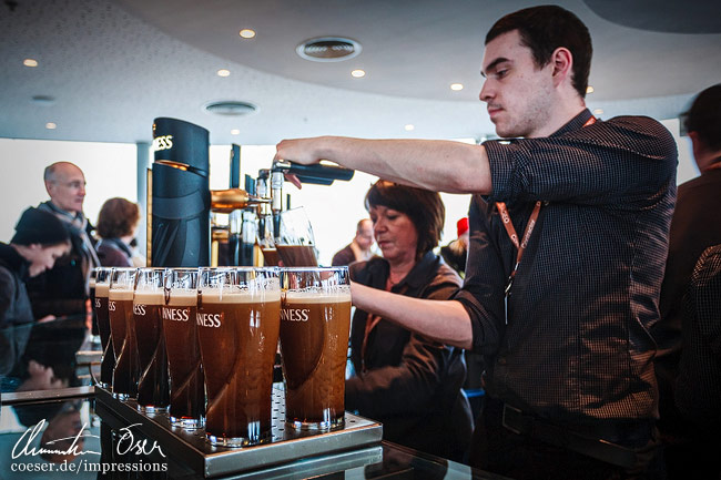 Ein Kellner schenkt mehrere Pints Guinness aus im Guinness Storehouse in Dublin, Ireland.