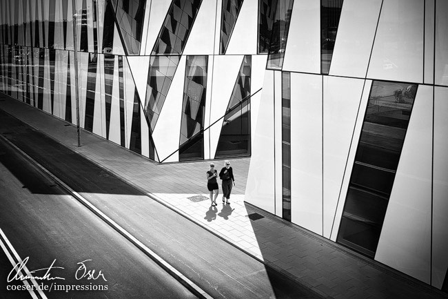 Zwei Frauen gehen an der Fassade des Bella Sky Hotels mit moderner Architektur vorbei in Kopenhagen, Dänemark.