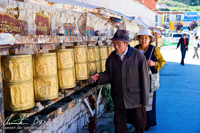 Zwei Pilger benutzen Gebetsmühlen beim Potala Palast in Lhasa, Tibet.