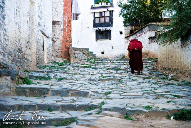 Eine Pilgerin geht einen beschwerlichen Weg hinauf in Lhasa, Tibet.