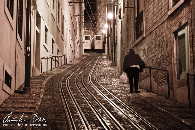 Eine Frau steigt nach Betriebsschluss der Ascensor da Lavra Standseilbahn eine steile Straße hinauf in Lissabon, Portugal.