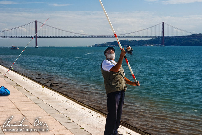 Tag und Nacht lieben es die Fischer, vor der Ponte 25 de Abril Brücke ihre Arbeit zu verrichten in Lissabon, Portugal.
