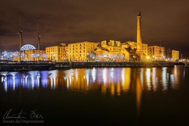 Das beleuchtete historische Hafenviertel Albert Dock spiegelt sich im Wasser in Liverpool, UK.