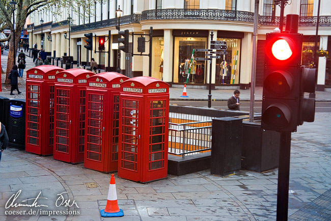 Vier Telefonzellen und eine rote Ampel in London, Großbritannien.