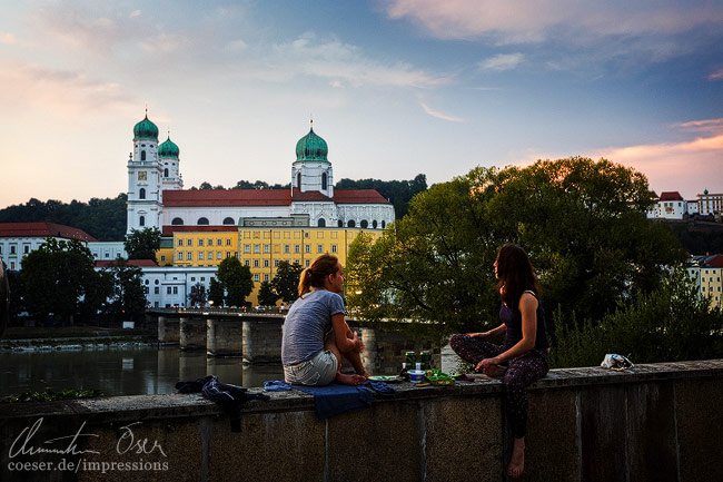 Zwei Mädchen genießen einen lauen Abend vor dem Passauer Stephansdom in Passau, Deutschland.