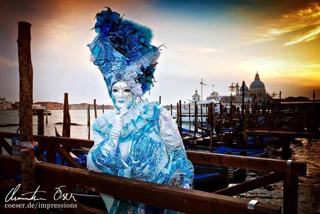 Eine verkleidete Frau posiert vor Gondeln während des Karnevals von Venedig, Italien.