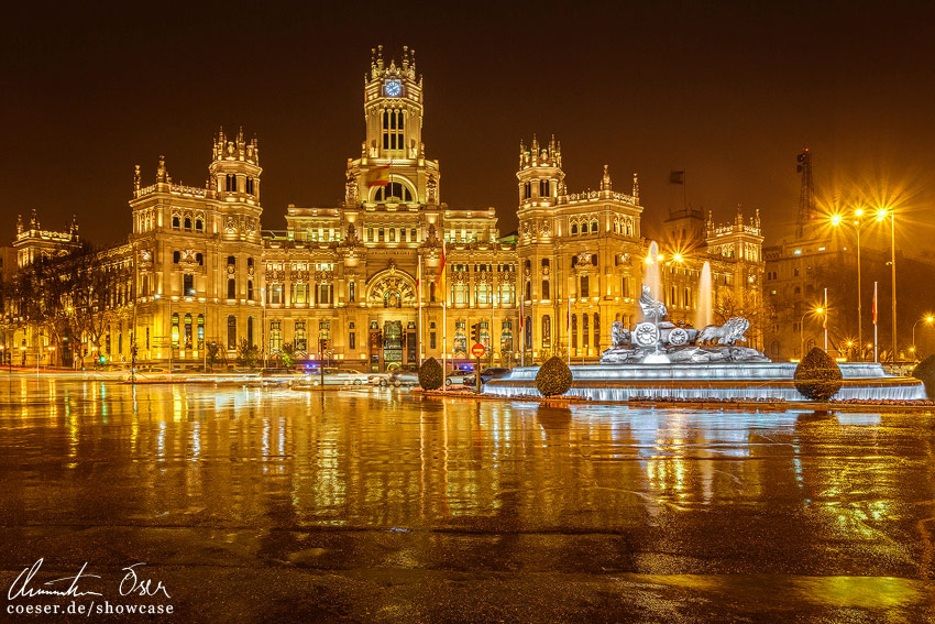 Der beleuchtete Platz Plaza de Cibeles und der Brunnen Fuente de Cibeles während heftigen Regens in Madrid, Spanien.